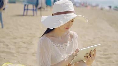 4K少女草帽坐沙滩操作平板电脑视频的预览图
